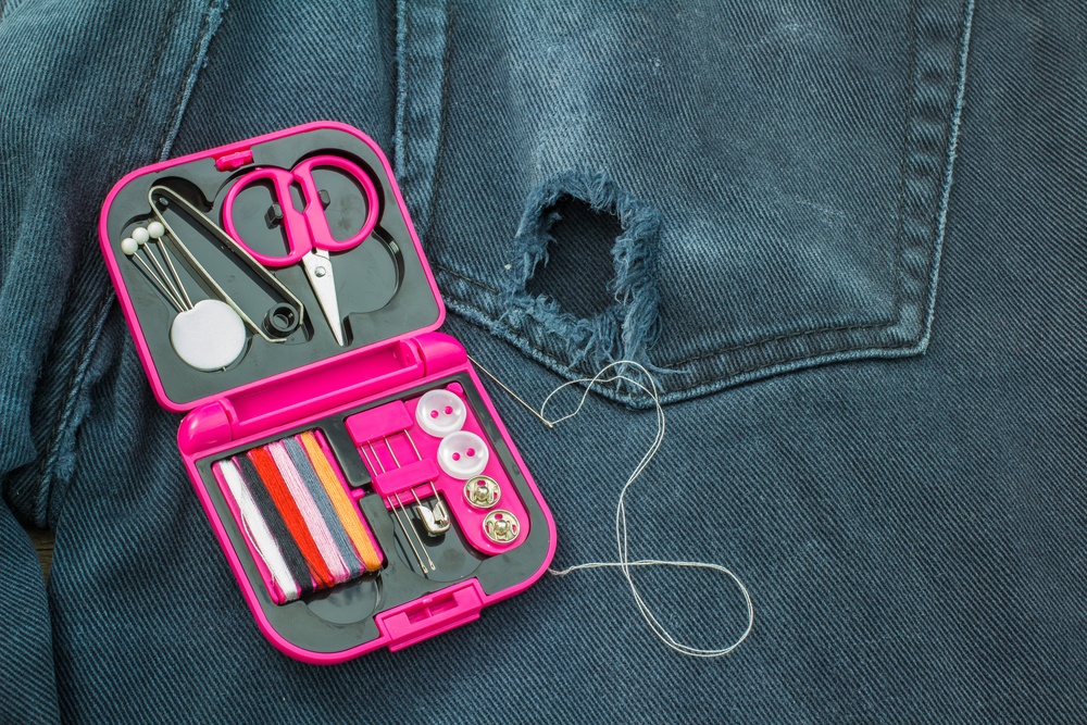 mini sewing kit placed over black jeans